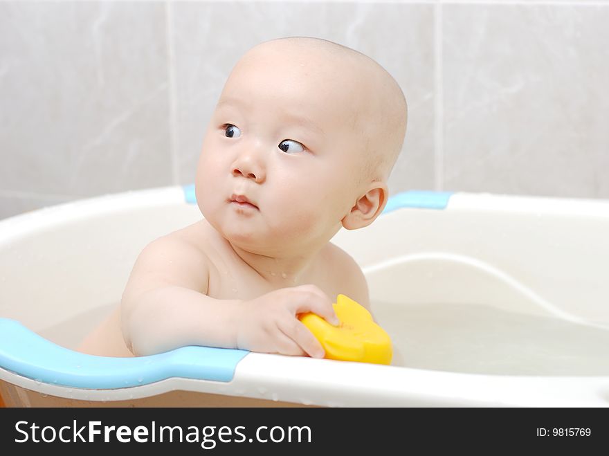 Asian baby boy holding a yellow plastic duck in bath. Asian baby boy holding a yellow plastic duck in bath