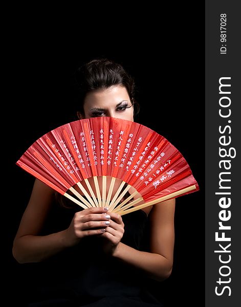 Beautiful woman with fan on  black background