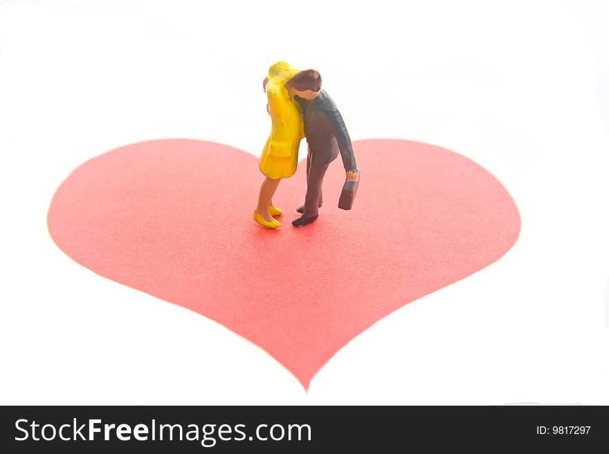 Miniature figures embracing on a red heart. Miniature figures embracing on a red heart.