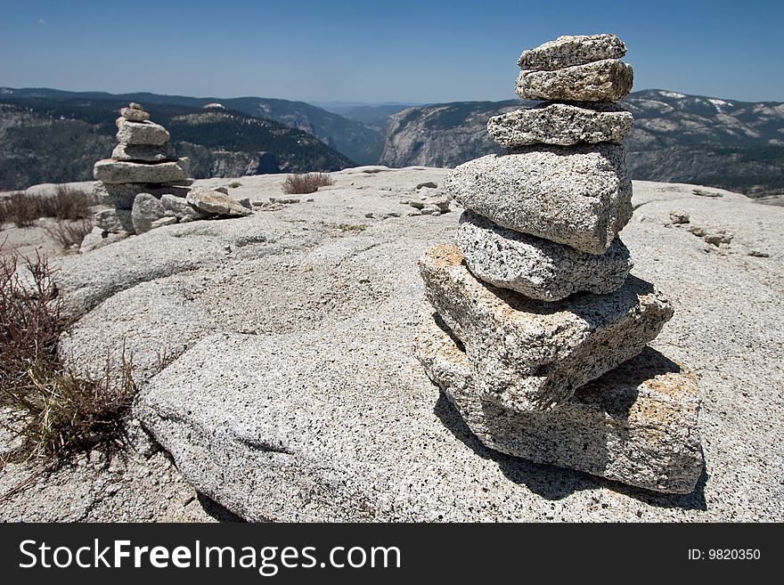 Two cairns at the peak of Half Dome; Yosemite Valley in the background.