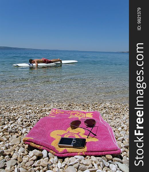 Boy lying on surfs, on the beach is cellular and sun glasses. Boy lying on surfs, on the beach is cellular and sun glasses