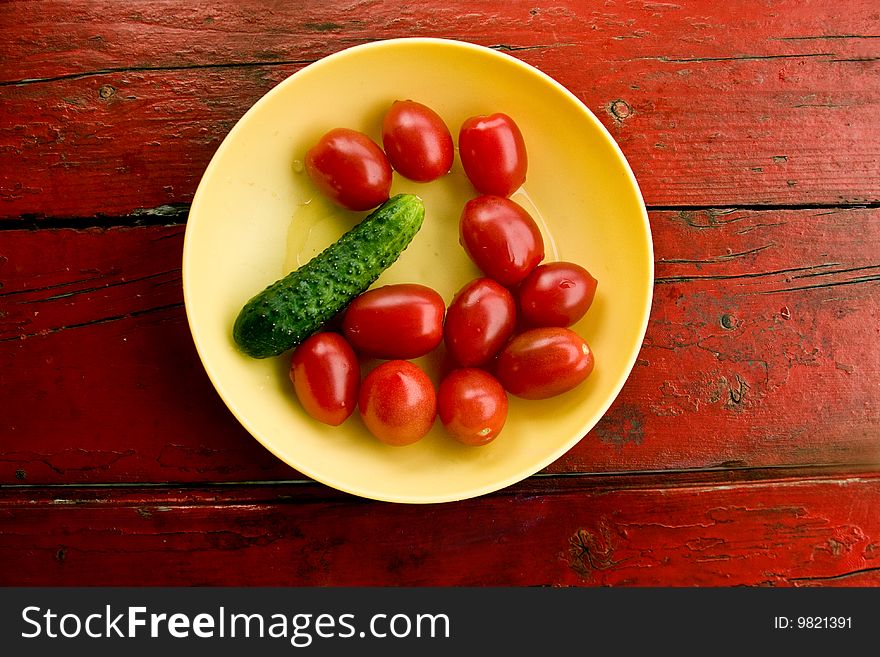 Summer vegetables tomatoes and a cucumber on a yellow plate. Summer vegetables tomatoes and a cucumber on a yellow plate