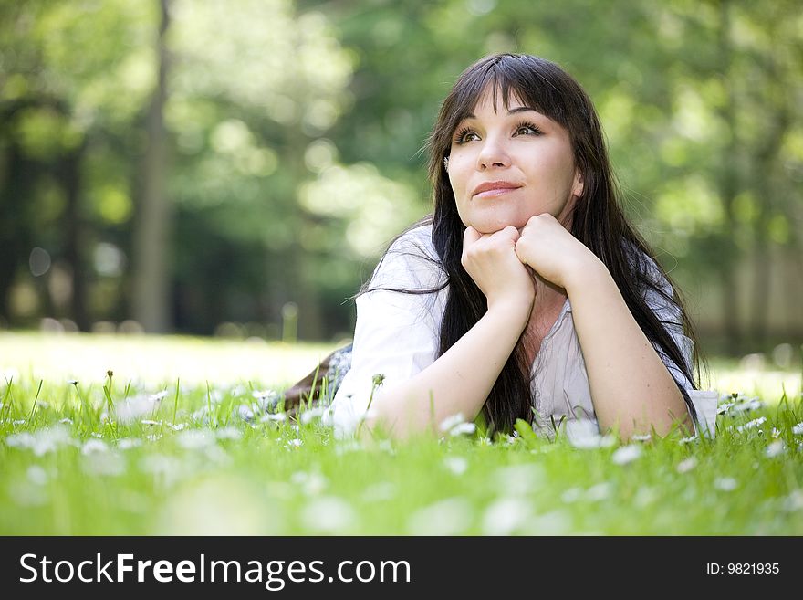 Attractive brunette woman relaxing on grass. Attractive brunette woman relaxing on grass