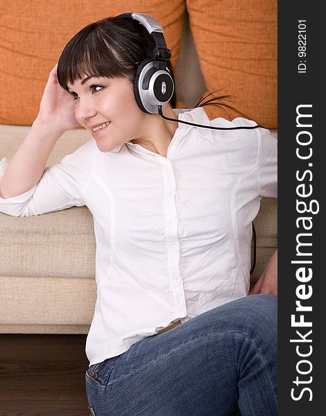 Attractive brunette woman with headphones sitting on floor. Attractive brunette woman with headphones sitting on floor