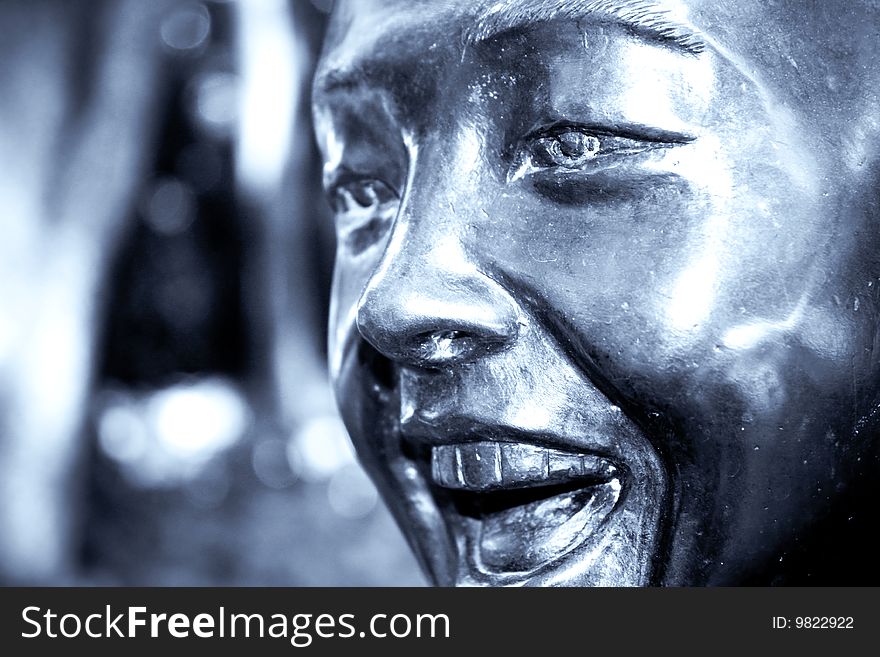 A metallic sculpture of a young boy laughing in selenium tone. A metallic sculpture of a young boy laughing in selenium tone