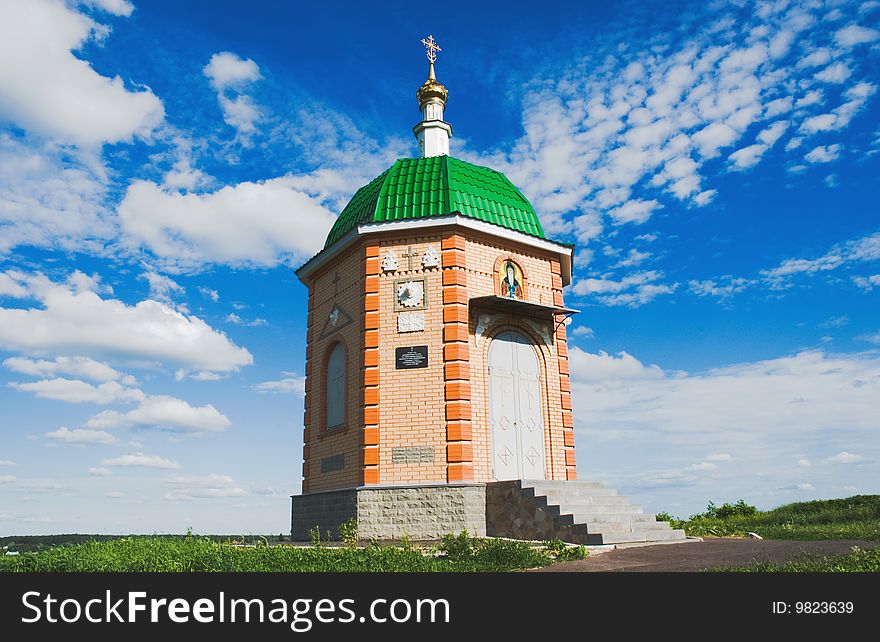 A small chapel on a background of blue sky with clouds