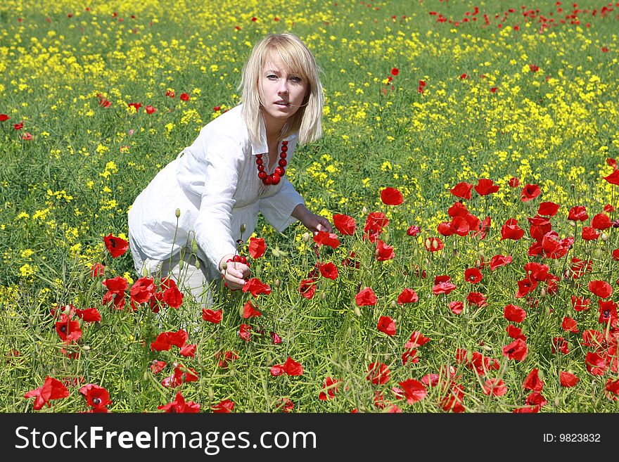 Blonde on the meadow assembles red poppies. Blonde on the meadow assembles red poppies