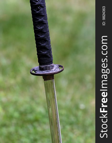 Samurai sword stuck in the ground with a field in teh background. Samurai sword stuck in the ground with a field in teh background.