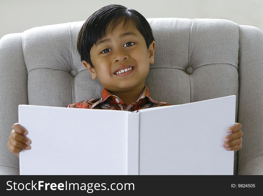 A 5 year old boy (asian origin) smiling while holding a book. A 5 year old boy (asian origin) smiling while holding a book.