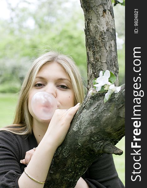 Playful blond girl blowing bubble with bubble gum. Playful blond girl blowing bubble with bubble gum