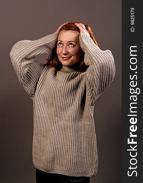 Smiling red haired woman in sweater isolated over gray