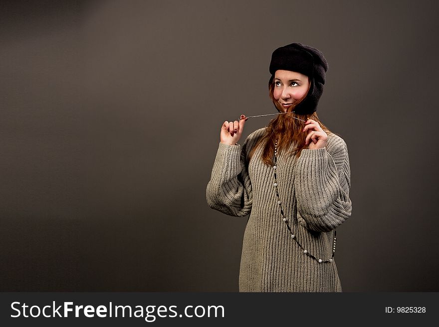 Smiling red haired girl in winter hat separated over grey