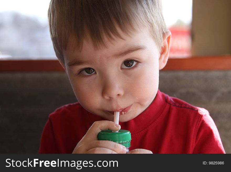 A young boy drinking juice through a straw.