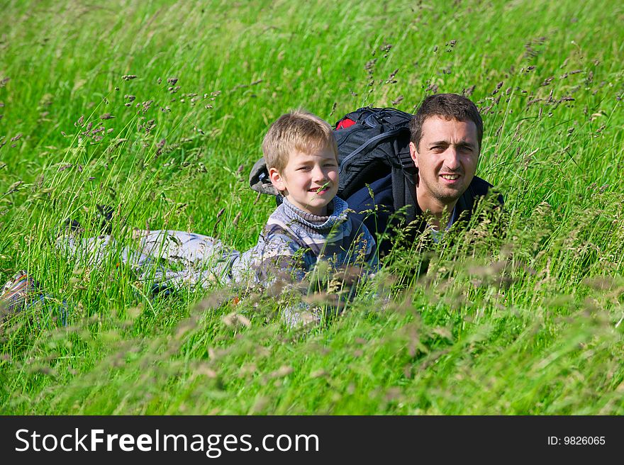 The man and the boy lie in a grass and smile. The man and the boy lie in a grass and smile