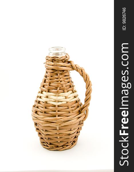 A glass bottle with wicker weaved closely around it with a handle. There is no cork in the neck of the bottle. A glass bottle with wicker weaved closely around it with a handle. There is no cork in the neck of the bottle.