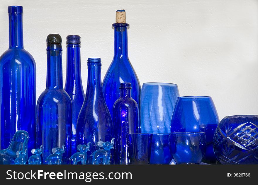 Bottles, glasses and items of blue glass together on a shelf. Bottles, glasses and items of blue glass together on a shelf.