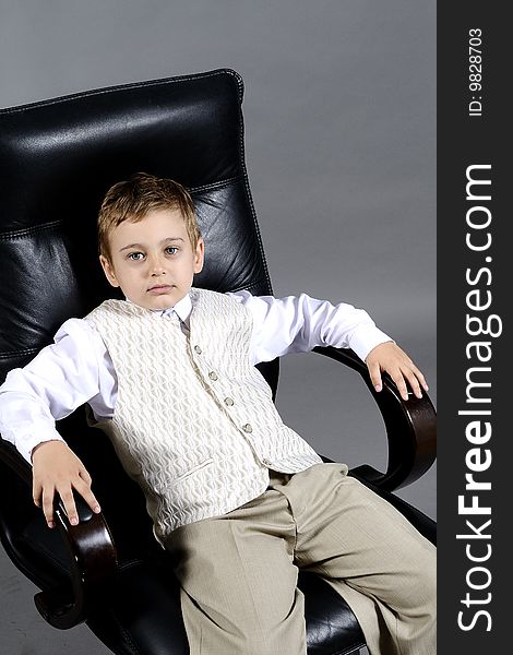 Close-up of small boy sitting on chair in office. Close-up of small boy sitting on chair in office