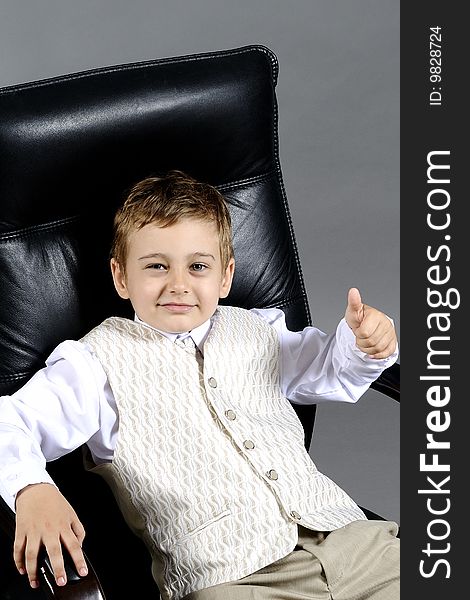 Close-up of small boy sitting on chair in office. Close-up of small boy sitting on chair in office