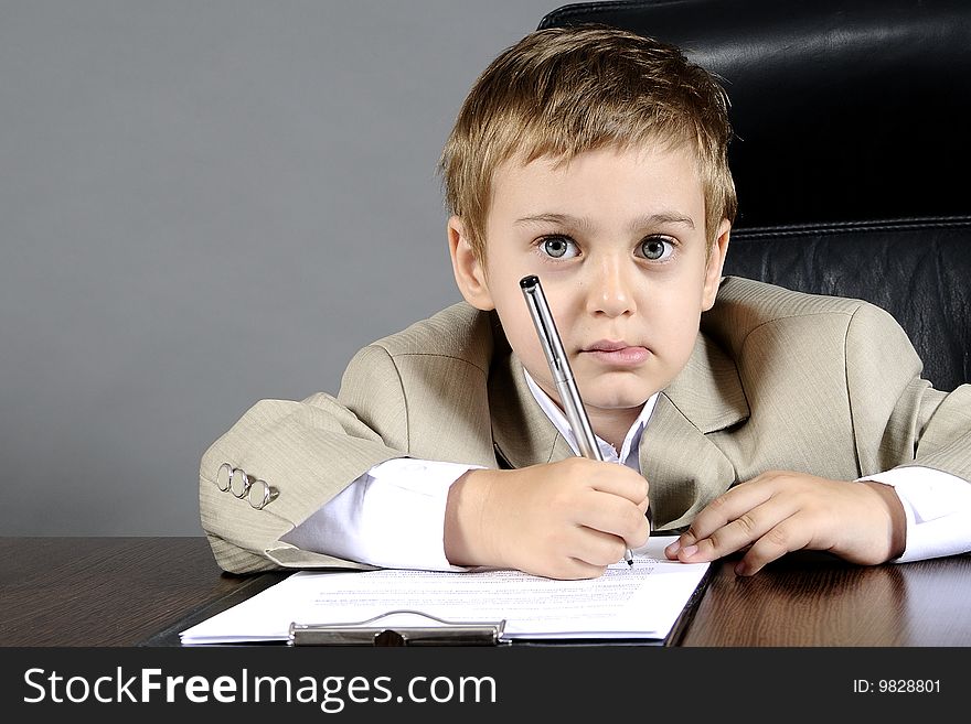 Close-up of small boy writting documents in office. Close-up of small boy writting documents in office