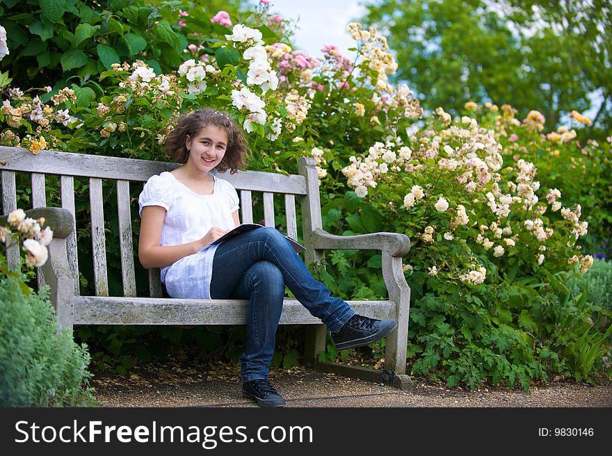 The girl with the open book sits on a bench and smiles. The girl with the open book sits on a bench and smiles