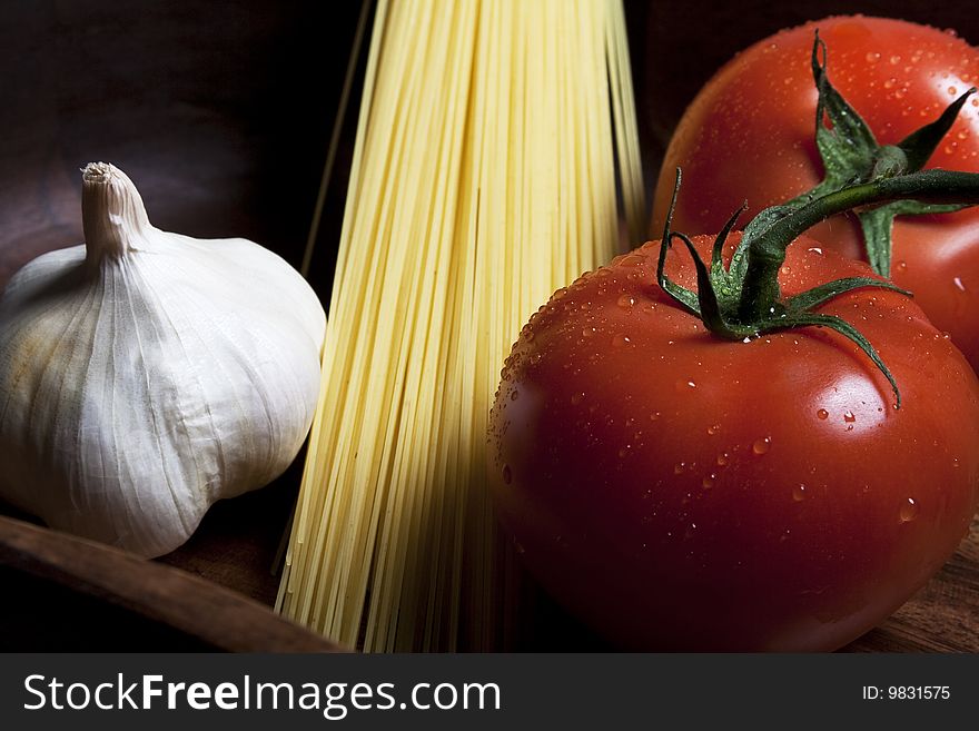 Red tomatos on a vine, pasta and garlic. Red tomatos on a vine, pasta and garlic