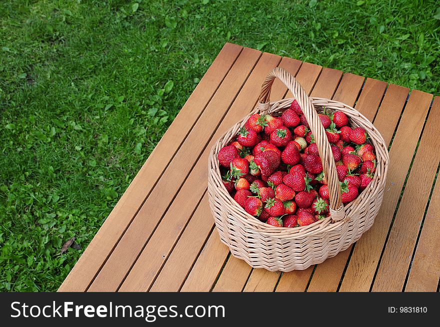 Red strawberry fruit in wooden basket on table