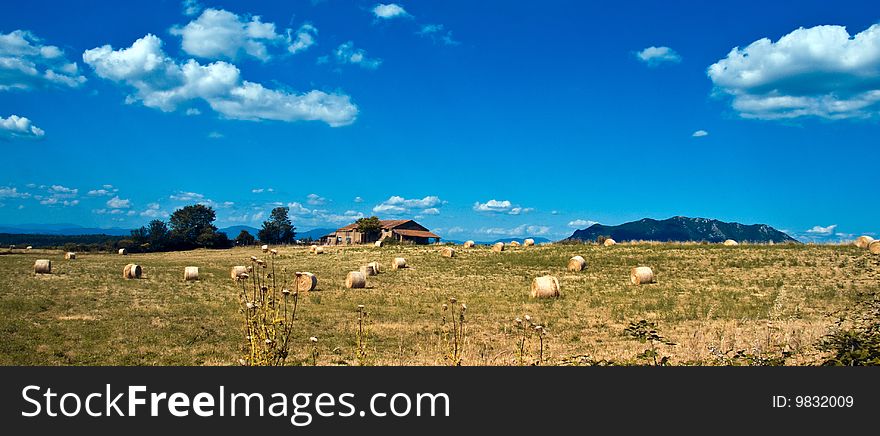 Bales of hay arount the farm and the mountains on the background