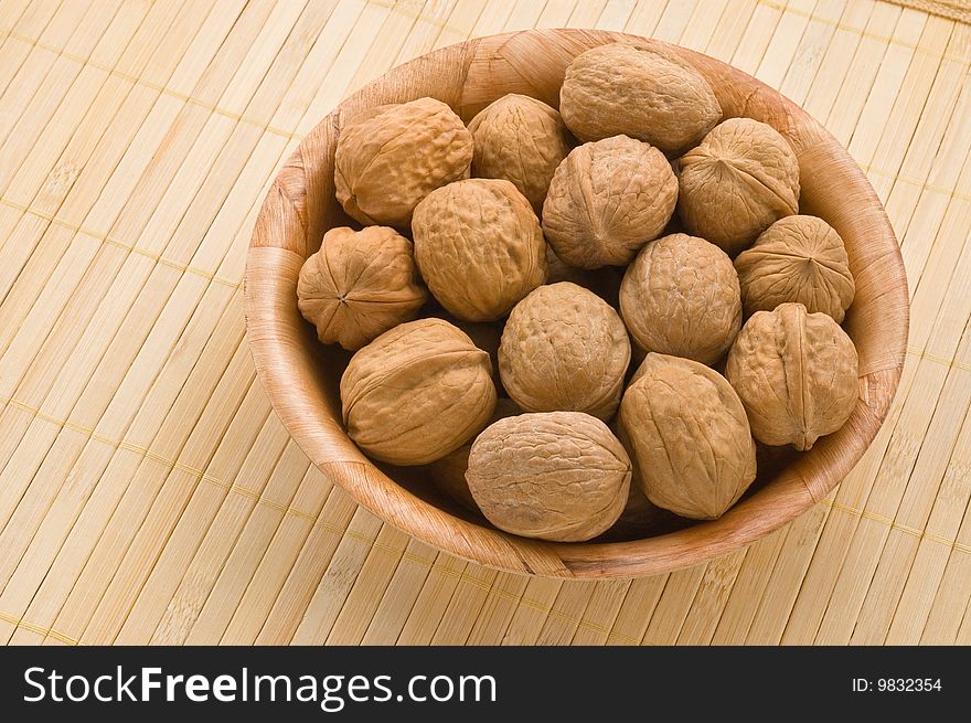 Bunch of walnuts in a bowl, over a bamboo mat. Bunch of walnuts in a bowl, over a bamboo mat.