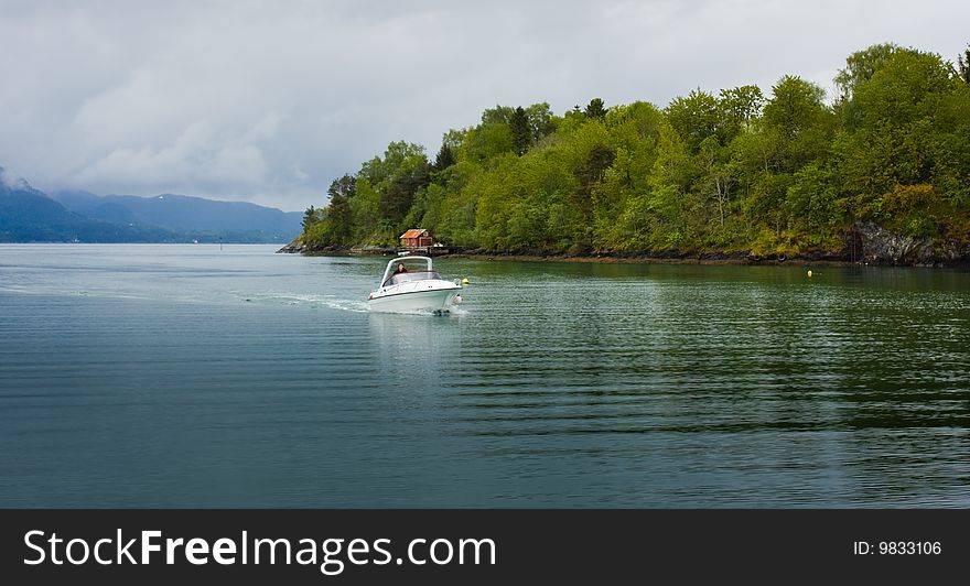 Boat in the sea in Norway. Small wooden house at the sea coast.