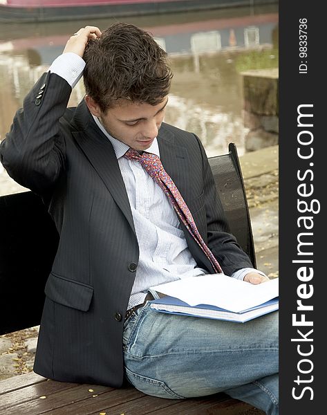 Young handsome man reading a document outside. Young handsome man reading a document outside