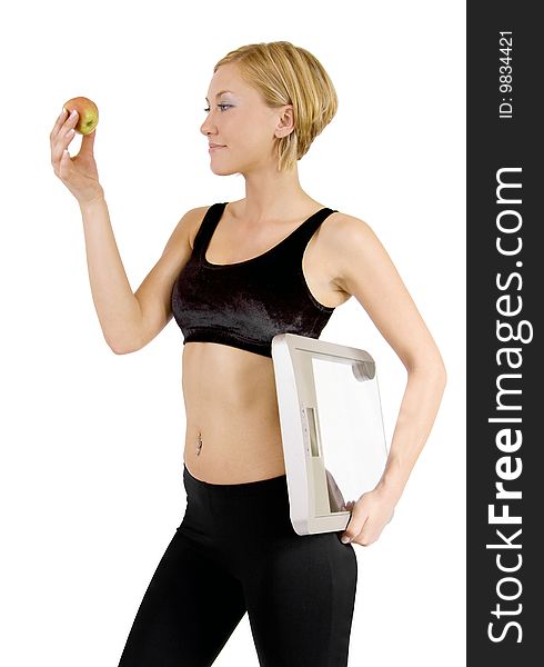 A beautiful blond Swedish woman is looking at an apple and hold a scale in the other hand. A beautiful blond Swedish woman is looking at an apple and hold a scale in the other hand