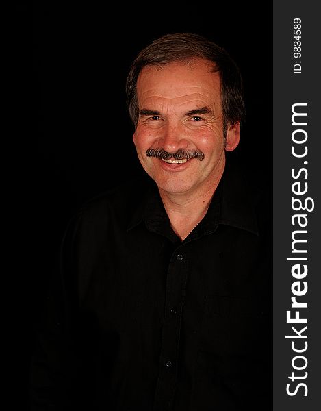 A smiling man on a black studio back ground