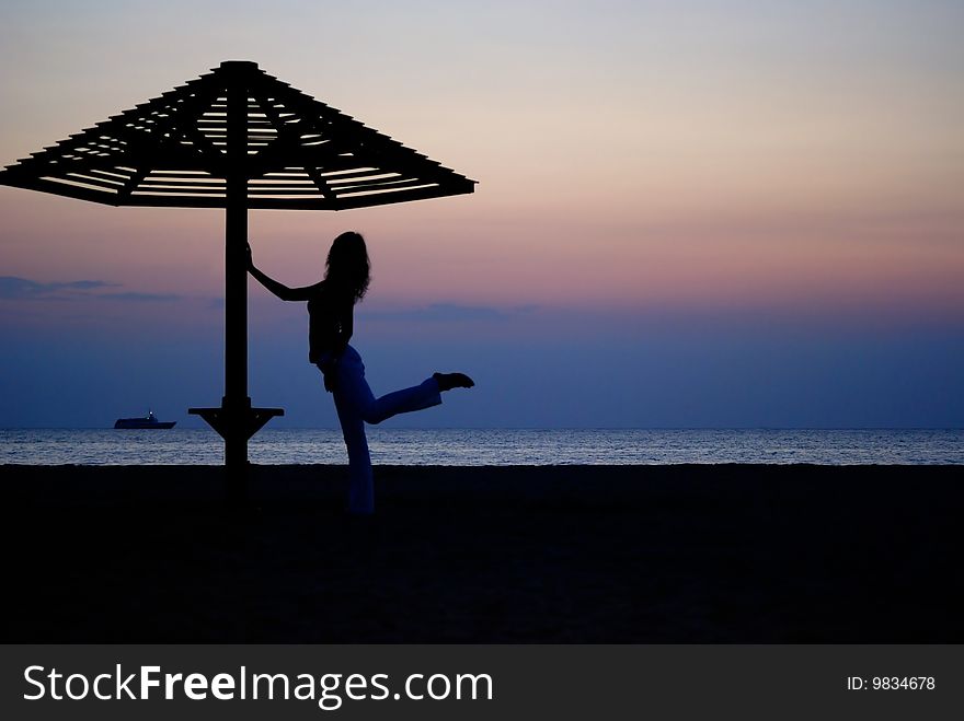 Beach umbrella and the girl silhouette on sunset. Beach umbrella and the girl silhouette on sunset