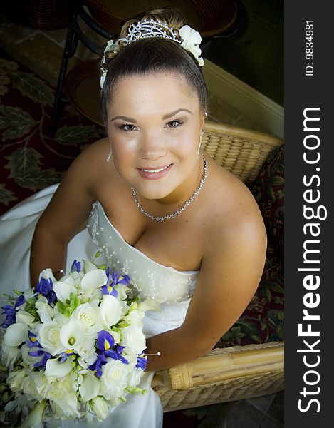 A beautiful smiling bride seated in a strapless dress holding flowers. A beautiful smiling bride seated in a strapless dress holding flowers.