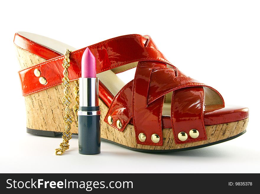 Single red shoe with pink lipstick and gold bracelet with clipping path on a white background. Single red shoe with pink lipstick and gold bracelet with clipping path on a white background