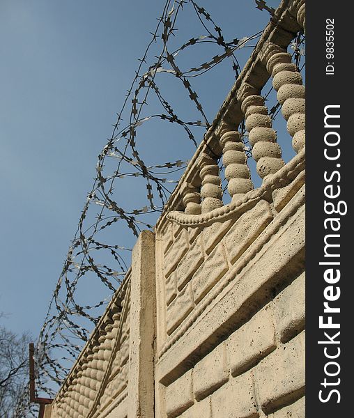 Barbwire and wall under blue sky