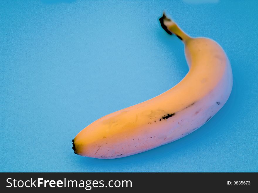 It's a single banana against a light aqua blue background. It's a single banana against a light aqua blue background