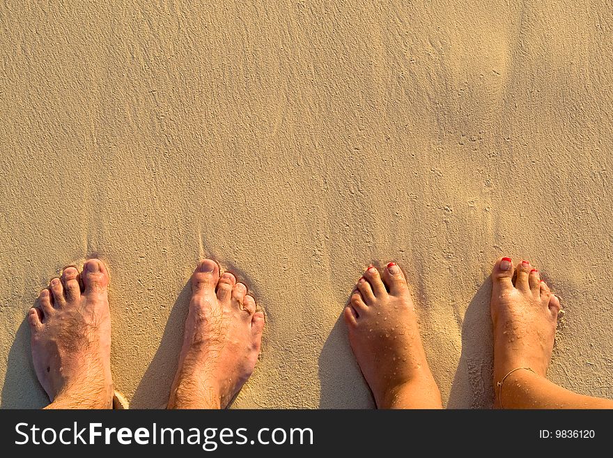 Tanned legs on sand beach in summer
