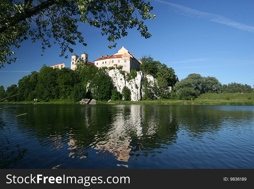Benedictine Abbey in Tyniec near Cracow in Poland (Krakow). Monastery has been built on rocks above Vistula river in 1044. Monastry mirrors in a river and the tree hangs above the building.