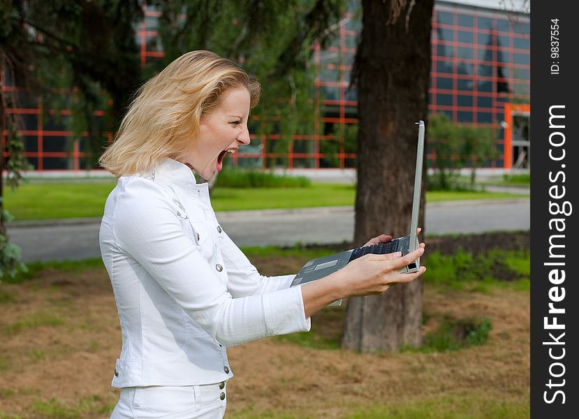 Young woman in a white suit holds a laptop and shouts on it. Young woman in a white suit holds a laptop and shouts on it