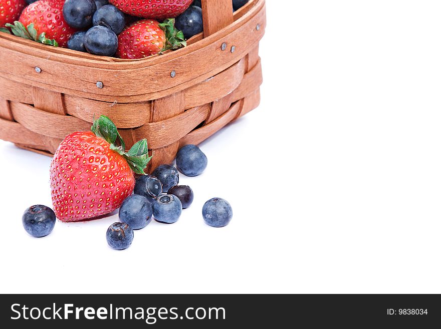 A small basket of fresh strawberries and blueberries on white background. A small basket of fresh strawberries and blueberries on white background.