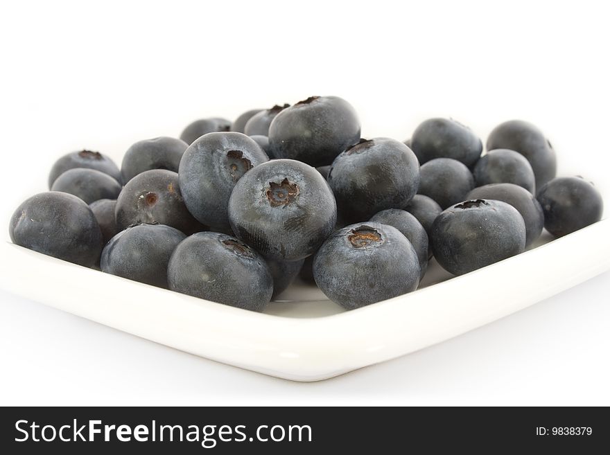 A plate with fresh blueberries isolated on white background, with shadow.