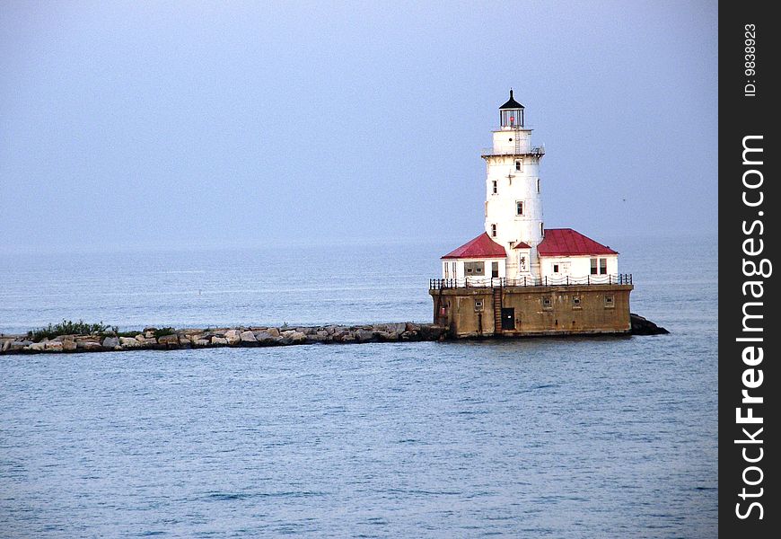 A lighthouse at the end of a pier on a lake