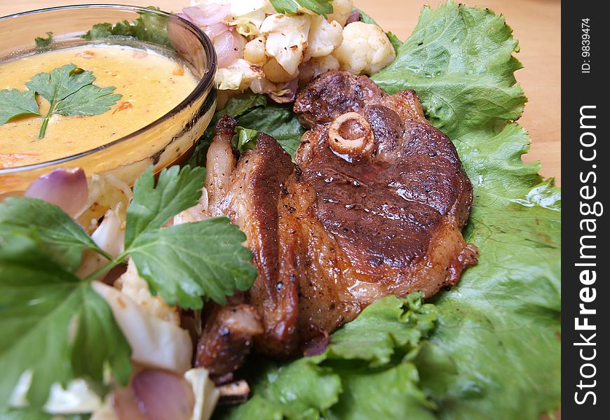 Close-up juicy tantalizing roasted lamb chop on salad bed and mustard gravy picture one. Close-up juicy tantalizing roasted lamb chop on salad bed and mustard gravy picture one