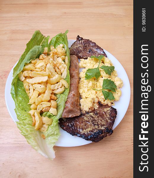 Plate of roasted beef cutlets salad fries eggs and bread on wood table surface. Plate of roasted beef cutlets salad fries eggs and bread on wood table surface