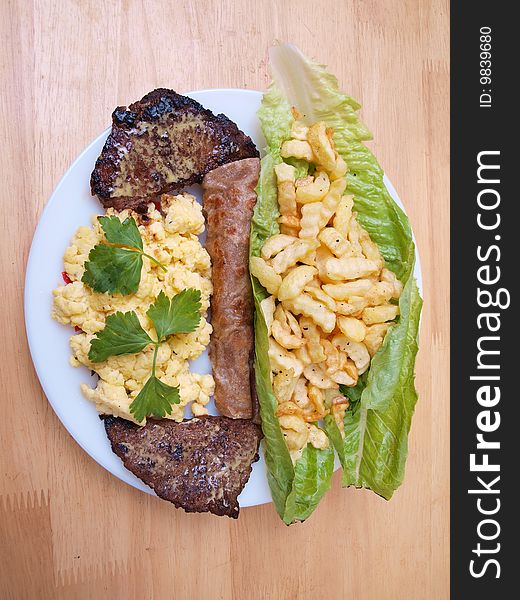 Plate of roasted beef cutlets salad fries eggs and bread on wood table surface picture two. Plate of roasted beef cutlets salad fries eggs and bread on wood table surface picture two