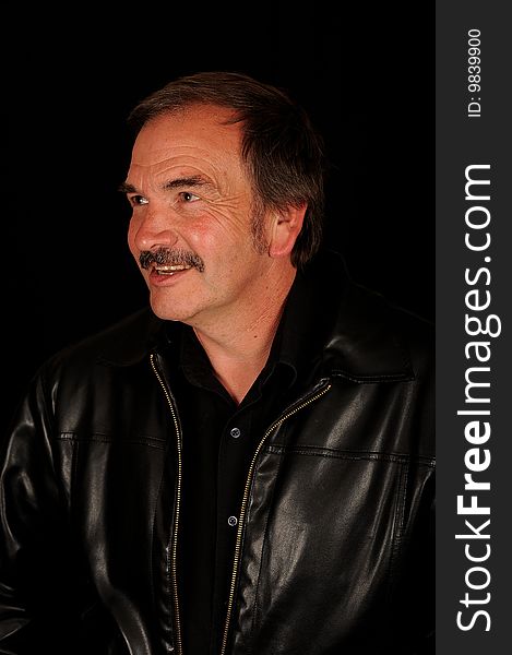 A smiling man on a black studio back ground