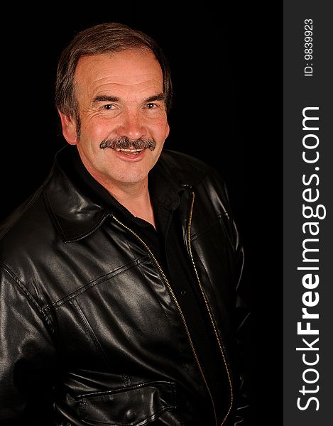 A smiling man on a black studio back ground