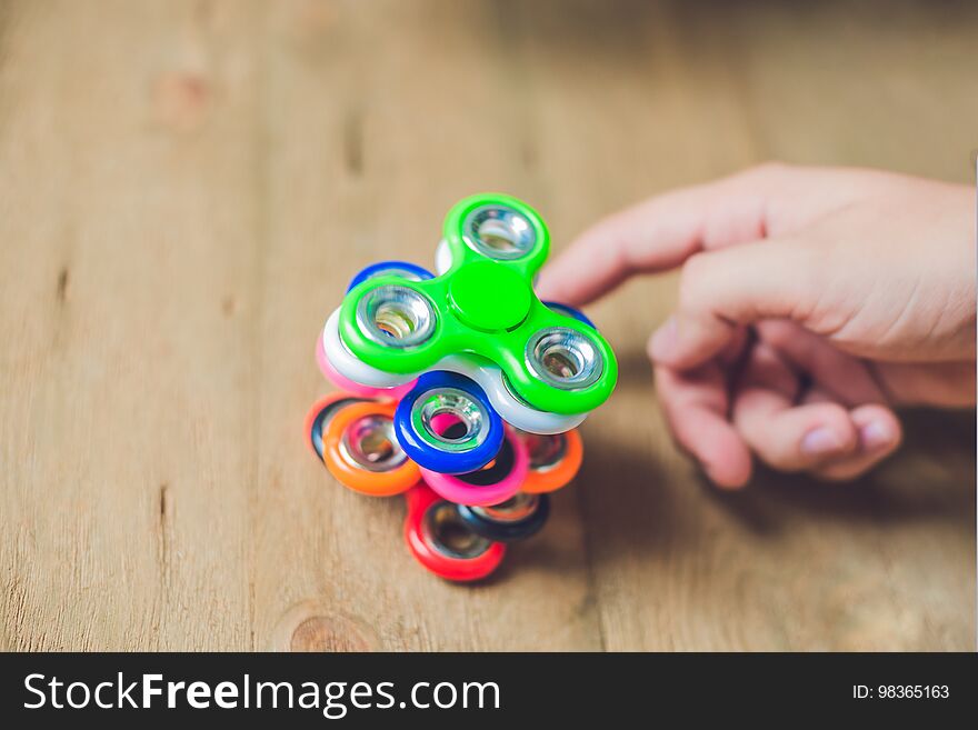 A man hand holding hand spinner or fidget spinner over wooden ba