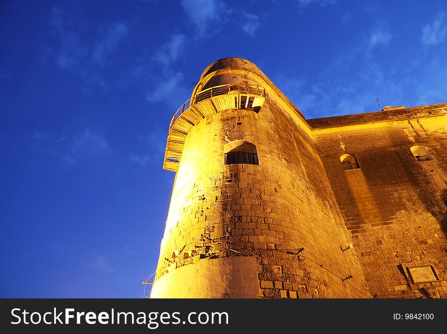 Close up of part of an ancient fortification on the maltese islands illuminated by a powerful light taken at twilight